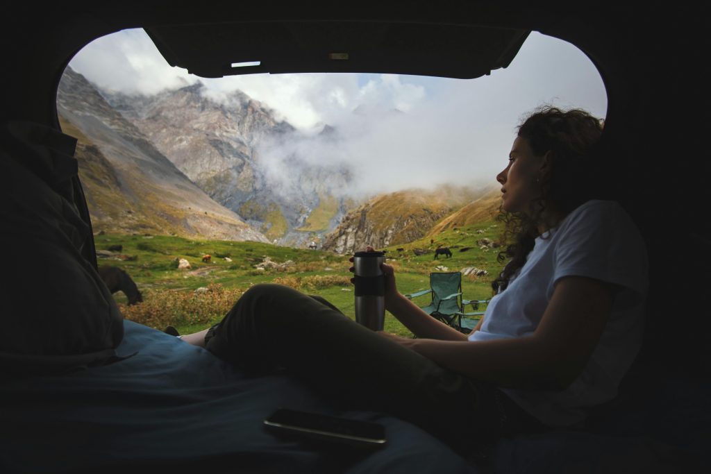 Eine Frau sitzt in einem Camper mit Blick auf die Natur