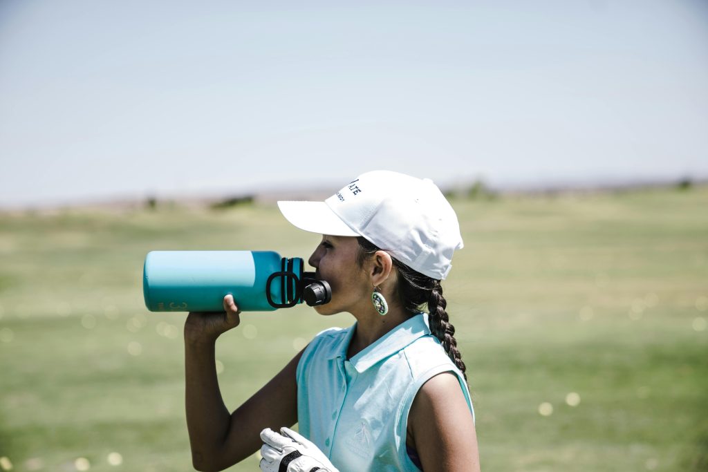 Eine Sportlerin trinkt aus einer Wasserflasche
