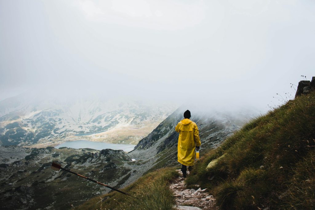 Eine Person mit eimem Regencape beim Wandern